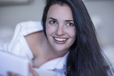 Portrait of smiling young woman with tablet in bed - ZEF12195