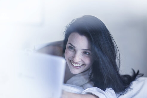 Lächelnde junge Frau im Bett mit Tablet - ZEF12197