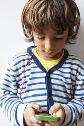 Little boy listening to the music of his smartphone with headphones - VABF00972