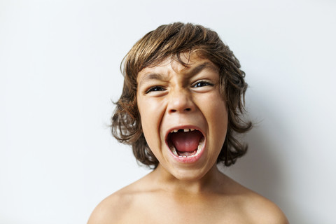 Portrait of screaming little boy with tooth gap in front of white background stock photo