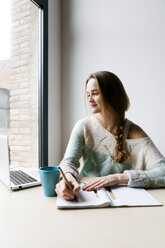 Young woman working with laptop at home - VABF00977