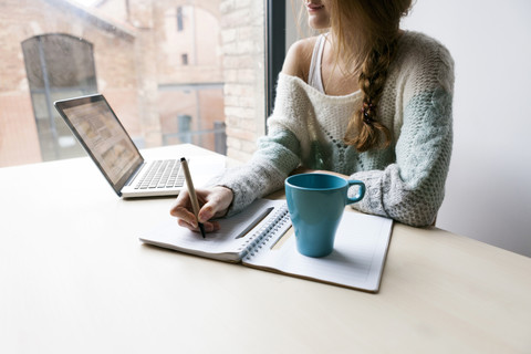 Young woman writing down something, partial view stock photo