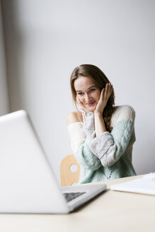 Aufgeregte junge Frau schaut auf ihren Laptop - VABF00981