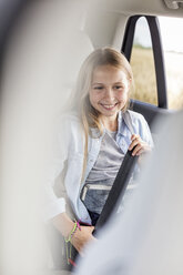 Girl sitting in car, fastening seat belt - WESTF22346