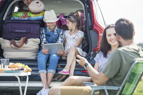 Glückliche Familie auf einer Autoreise, die eine Pause am Straßenrand einlegt, lizenzfreies Stockfoto