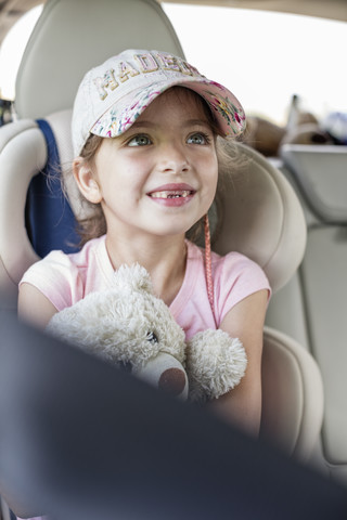 Mädchen sitzt im Auto und hält einen Teddybär, lizenzfreies Stockfoto