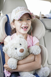 Girl sitting in car, holding teddy bear - WESTF22352