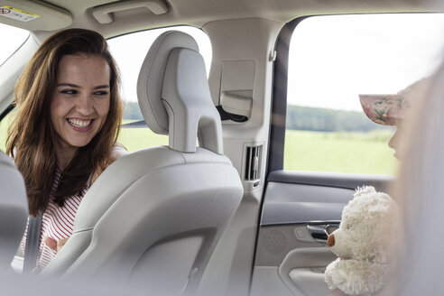 Mutter und Tochter auf Autoreise sitzen im Auto und halten einen Teddybär - WESTF22356