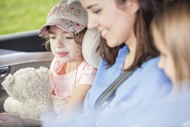 Mother and daughters on road trip sitting in car - WESTF22373