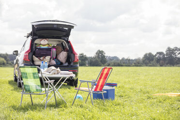 Car on meadow with open boot full of luggage - WESTF22375