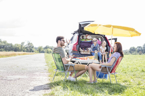 Glückliche Familie auf einer Autoreise, die eine Pause am Straßenrand einlegt - WESTF22378