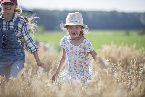 Two laughing girls running in field stock photo