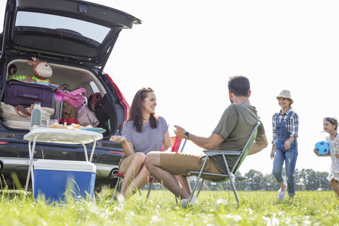 Glückliche Familie auf einer Autoreise, die eine Pause am Straßenrand einlegt, lizenzfreies Stockfoto