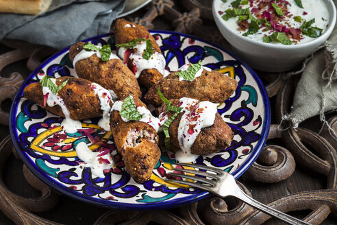 Kibbeh, orientalische Fleischkroketten mit Joghurtsoße auf einem Teller - SBDF03112