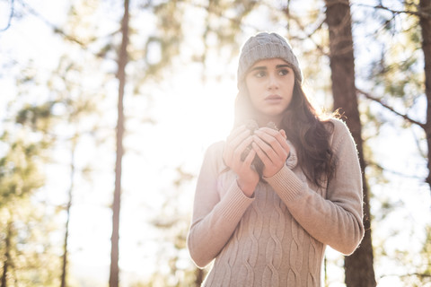 Porträt einer modischen jungen Frau mit Getränk im herbstlichen Wald, lizenzfreies Stockfoto