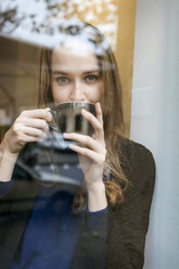Portrait of young woman in coffee shop drinking coffee - VABF00991