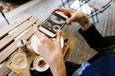 Frau in einem Straßencafé, die ihr Frühstück mit ihrem Mobiltelefon fotografiert - VABF00994