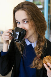 Junge Frau mit Muffin trinkt eine Tasse Kaffee - VABF00997