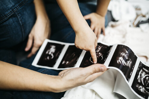 Kleiner Junge sieht sich Ultraschallbilder seiner schwangeren Mutter an, Teilansicht - JRFF01118