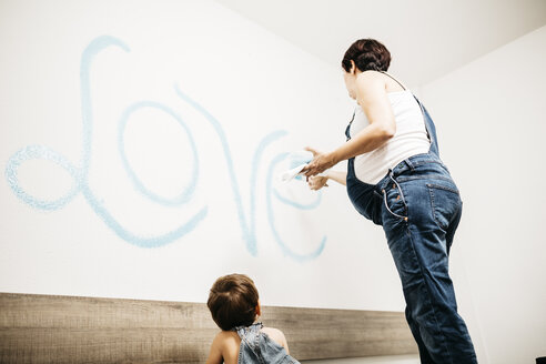 Little boy watching his mother painting the wall - JRFF01127