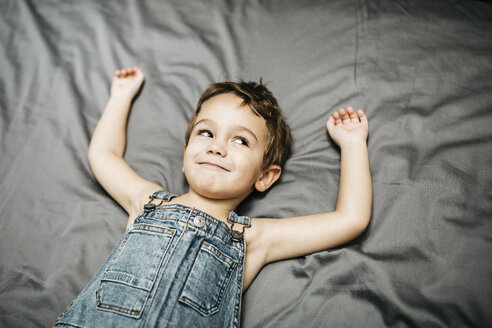 Lächelnder kleiner Junge auf dem Bett liegend - JRFF01131