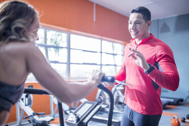 Fitness-Instrustor im Gespräch mit einer Frau auf einem Trainingsgerät - ZEF12260