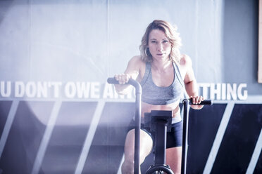 Young woman on exercise machine in gym - ZEF12261