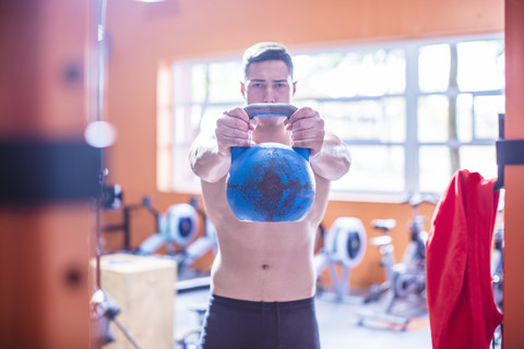 Junger Mann hebt Kettlebell im Fitnessstudio, lizenzfreies Stockfoto