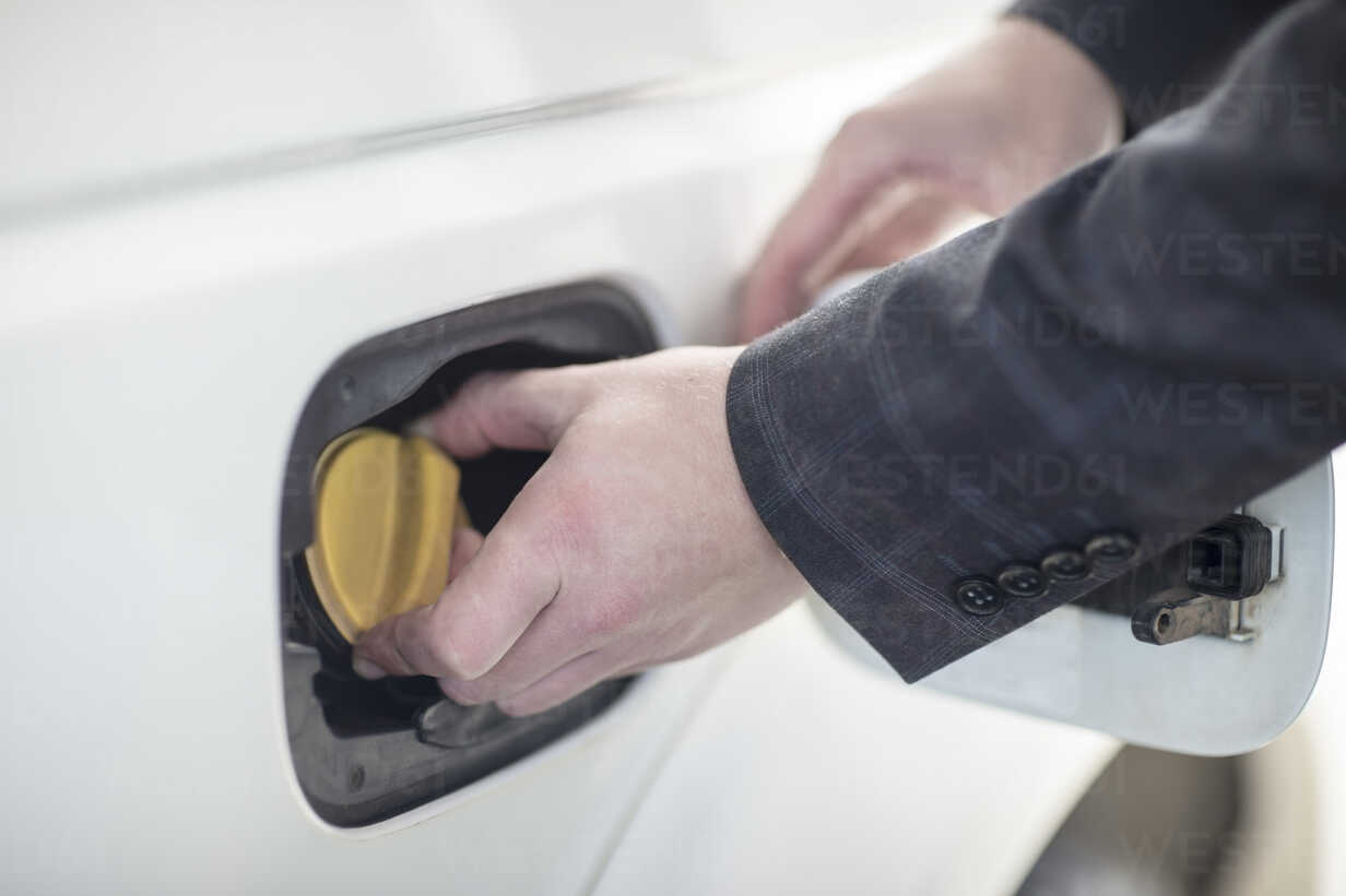 Eine person öffnet den tankdeckel eines autos an einer tankstelle