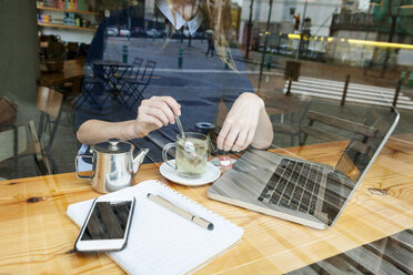 Junge Frau mit Laptop und Tasse Tee in einem Cafe, Teilansicht - VABF01004