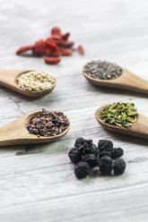 Wooden spoons of chia, cocoa, quinoa and moringa with chokeberries in the foreground - SARF03106