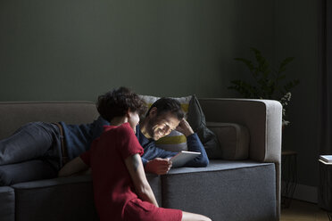 Couple relaxing together in the living room looking at tablet - RBF05459