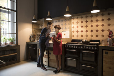 Ehepaar in der Küche mit Blick auf Tablet - RBF05471