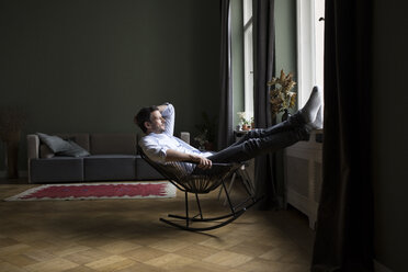 Man relaxing on rocking chair in his living room - RBF05480