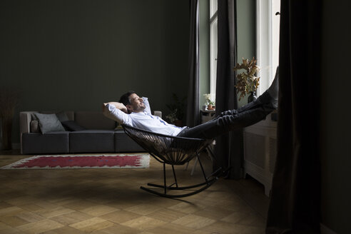 Man relaxing on rocking chair in his living room - RBF05481