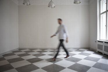 Mann durchquert leeren Raum einer Wohnung - RBF05493