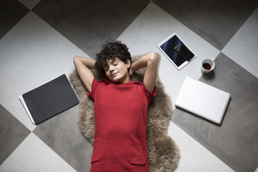 Portrait of young woman relaxing on the floor at home - RBF05517