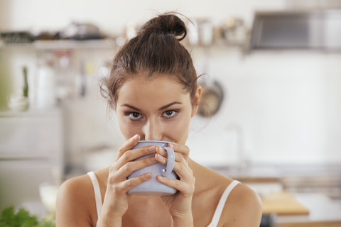 Junge Frau trinkt Kaffee in der Küche, lizenzfreies Stockfoto