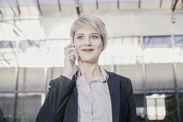 Portrait of smiling blond businesswoman on the phone - FMKF03436