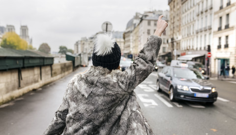 Frankreich, Paris, Rückenansicht einer jungen Frau, die ein Taxi ruft, lizenzfreies Stockfoto