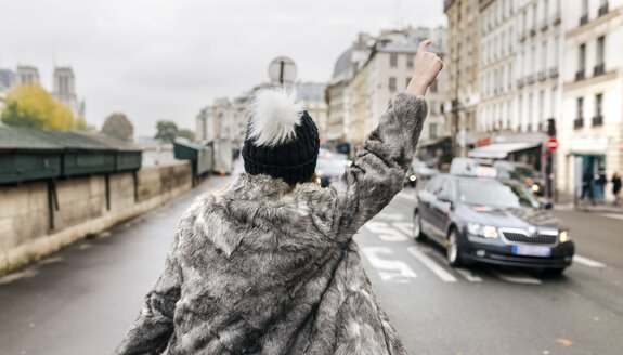 Frankreich, Paris, Rückenansicht einer jungen Frau, die ein Taxi ruft - MGOF02747