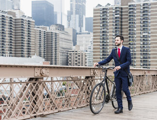 USA, New York City, Geschäftsmann mit Fahrrad auf der Brooklyn Bridge - UUF09633