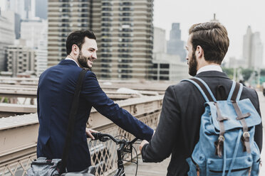 USA, New York City, zwei Geschäftsleute mit Fahrrad auf der Brooklyn Bridge - UUF09635