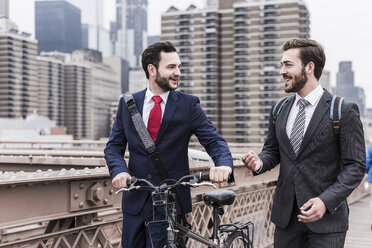 USA, New York City, zwei Geschäftsleute mit Fahrrad auf der Brooklyn Bridge - UUF09636