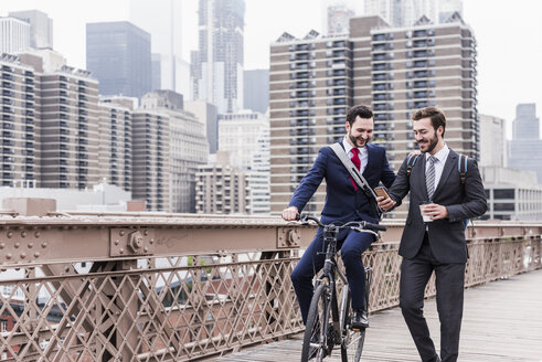 USA, New York City, zwei lächelnde Geschäftsleute auf der Brooklyn Bridge - UUF09637