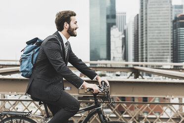 USA, New York City, Geschäftsmann auf Fahrrad auf der Brooklyn Bridge - UUF09639