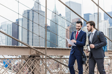 USA, New York City, zwei Geschäftsleute besprechen ein Dokument auf der Brooklyn Bridge - UUF09643