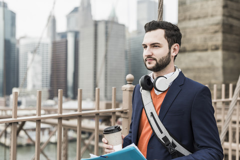 USA, New York City, Mann auf der Brooklyn Bridge mit Kaffee zum Mitnehmen, lizenzfreies Stockfoto