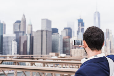 USA, New York City, man on Brooklyn Bridge taking cell phone picture - UUF09667