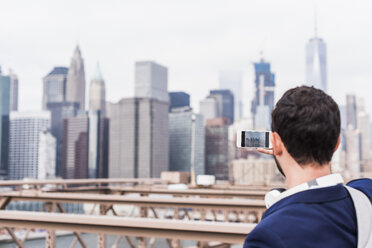 USA, New York City, Mann auf der Brooklyn Bridge beim Fotografieren mit dem Handy - UUF09667